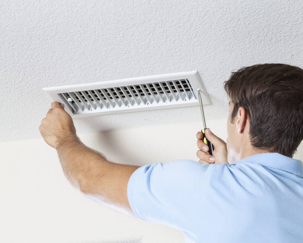 A man cleaning HVAC system air ducts in a home.