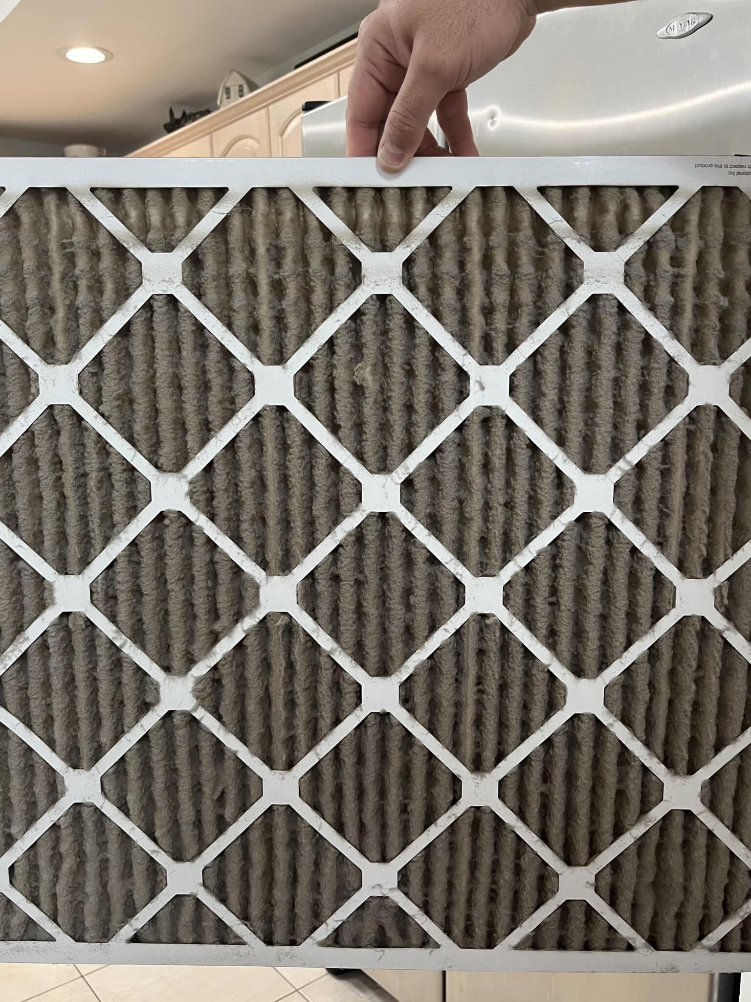 A man is holding a dirty HVAC filter that was removed. HVAC Filters by One Hour Heating & Air Conditioning of San Diego