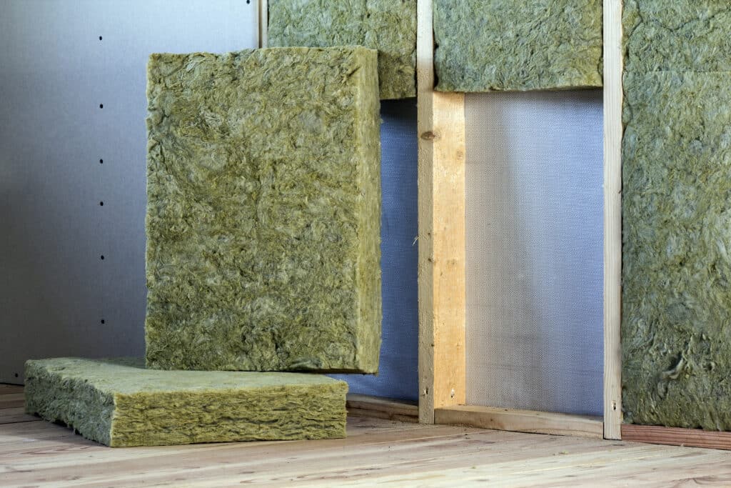 Wooden frame for future walls with drywall panels, insulated with rock wool and fiberglass home insulation for a cold barrier.