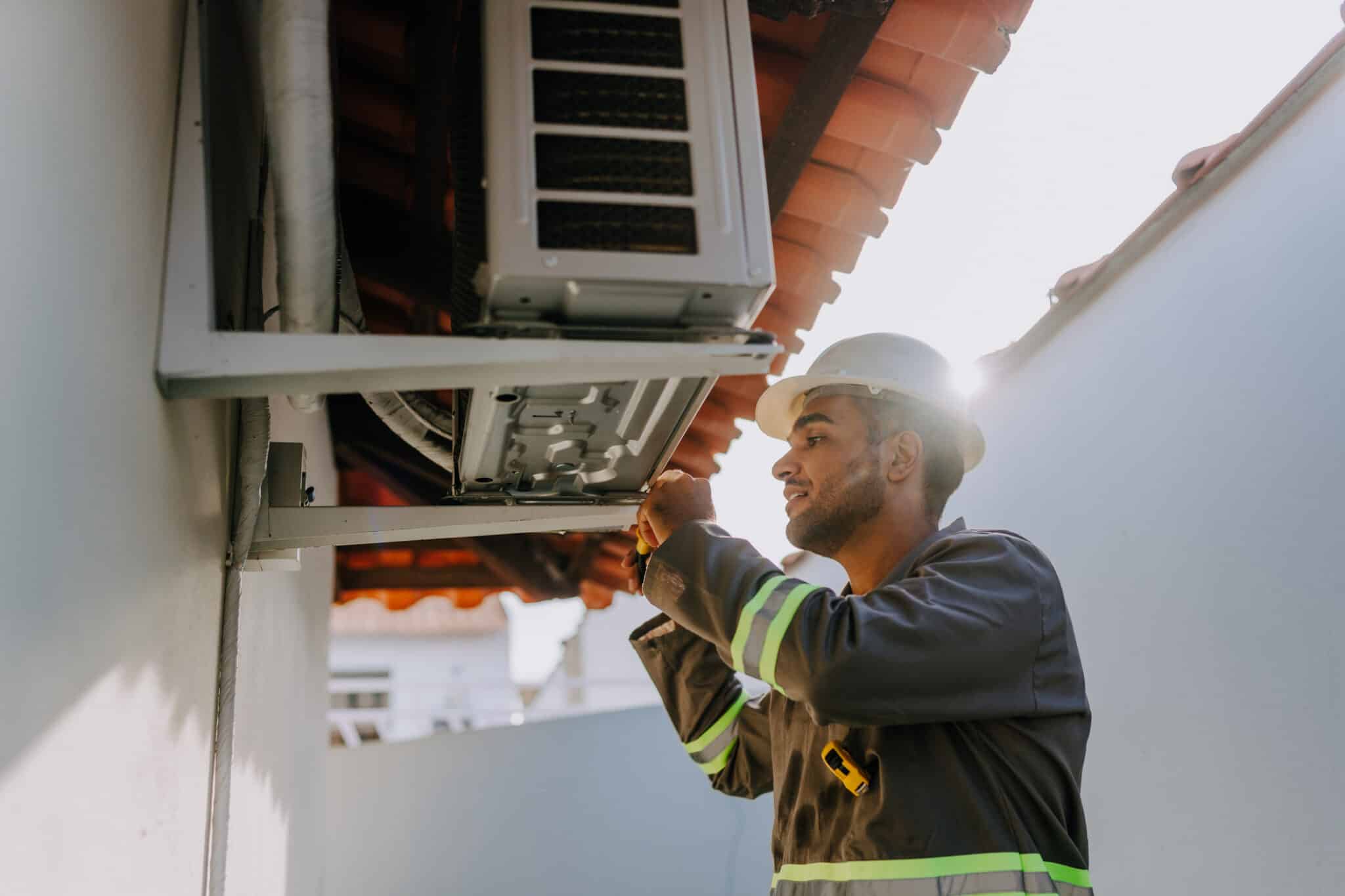 A technician inspecting an air conditioning unit, HVAC Care.