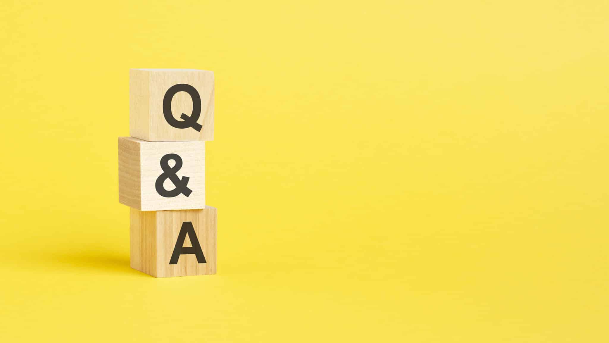 Q and A text on wooden block with yellow background, HVAC.